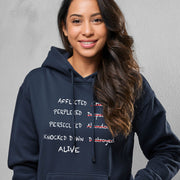 Woman wearing navy blue hoodie with graphic based on 2 Corinthians 4:8–9